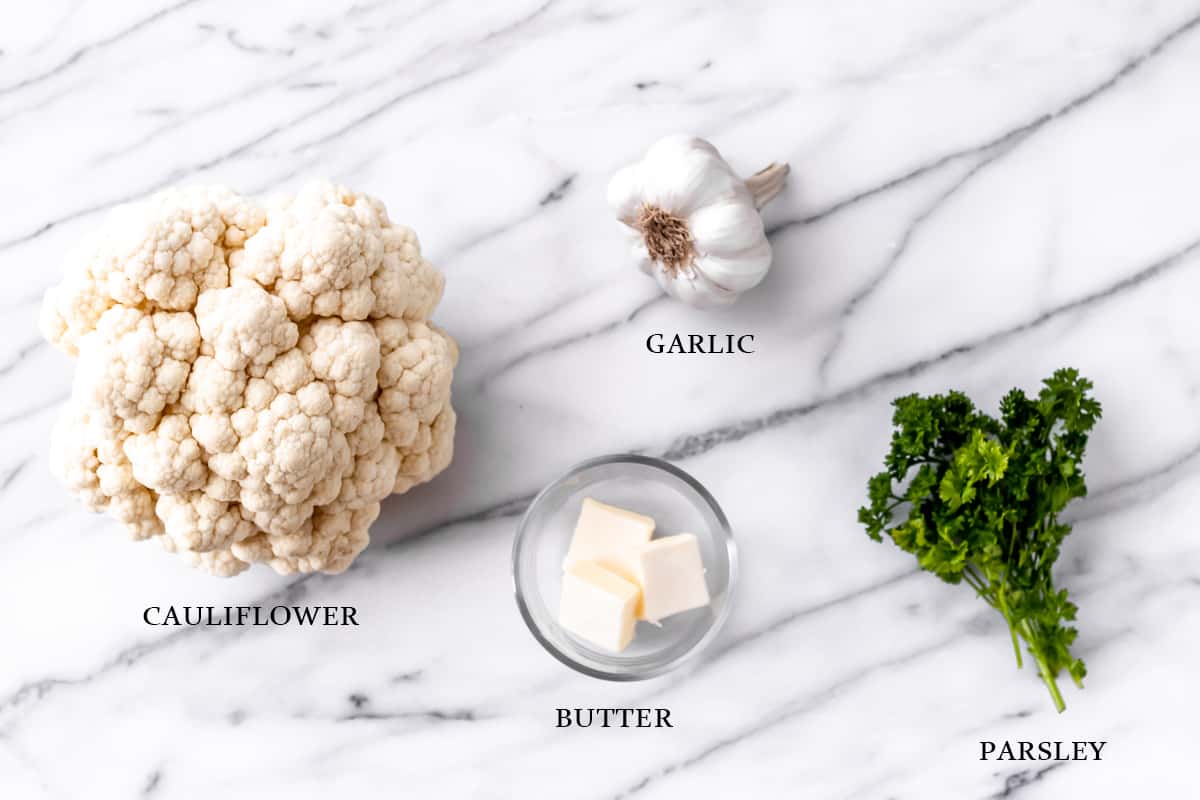 Ingredients needed to make garlic cauliflower rice on a marble background with text overlay