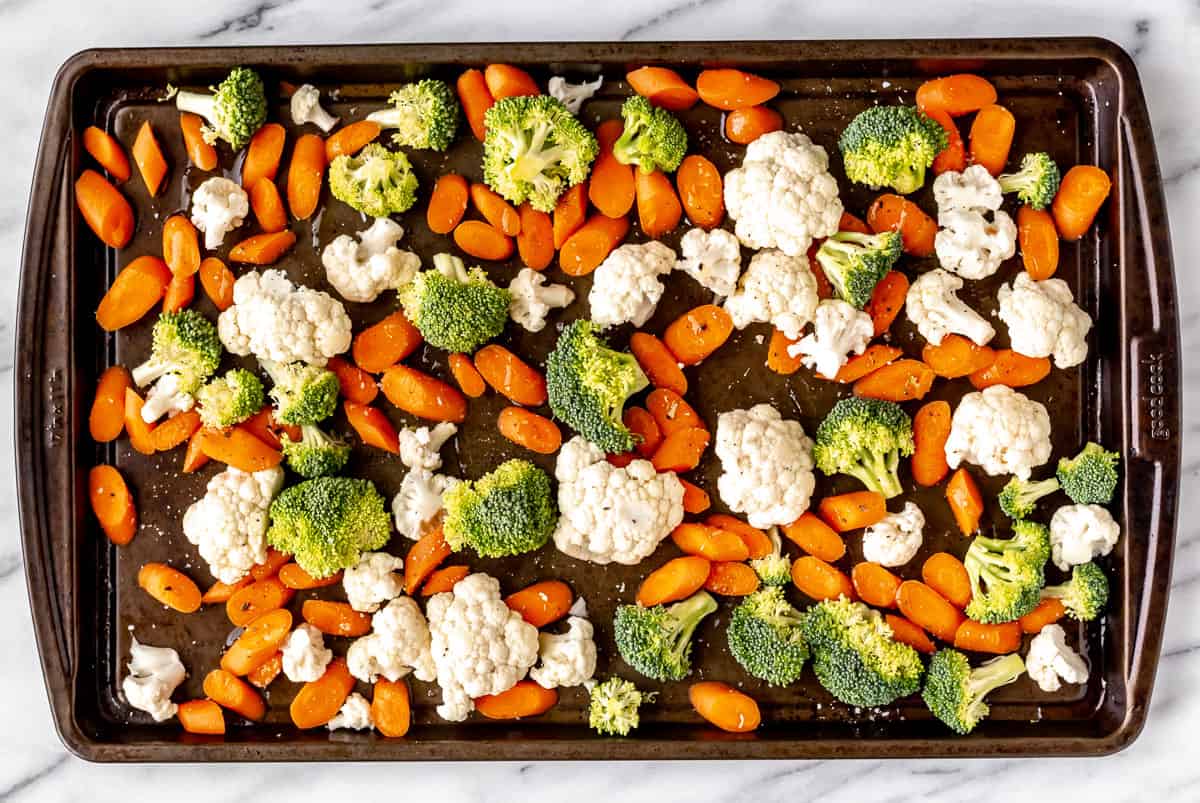 Raw broccoli, carrots and cauliflower spread onto a sheet pan with olive oil, salt and pepper.