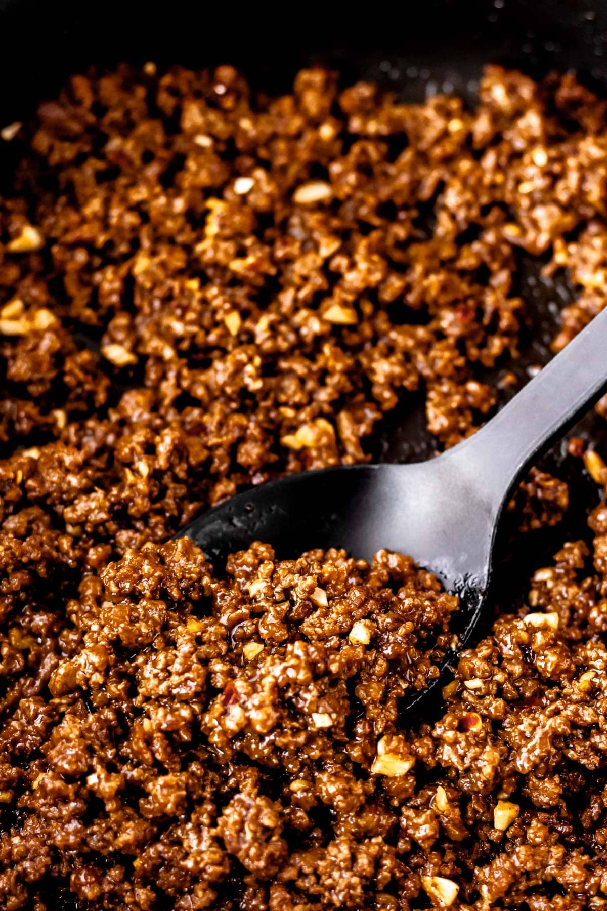 Close up of Mongolian ground beef with a black spoon in it.