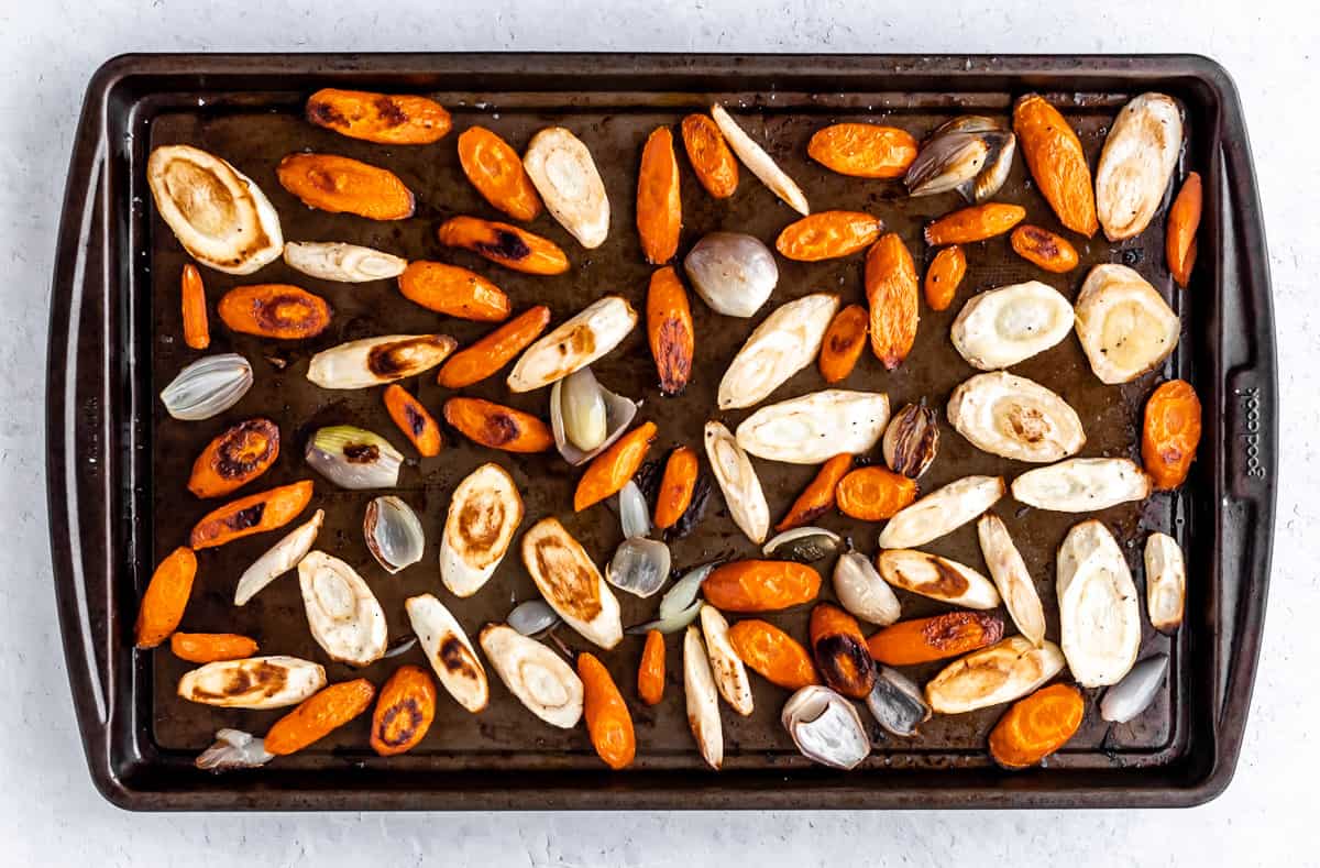 Roasted carrots and parsnips slices on a baking sheet.