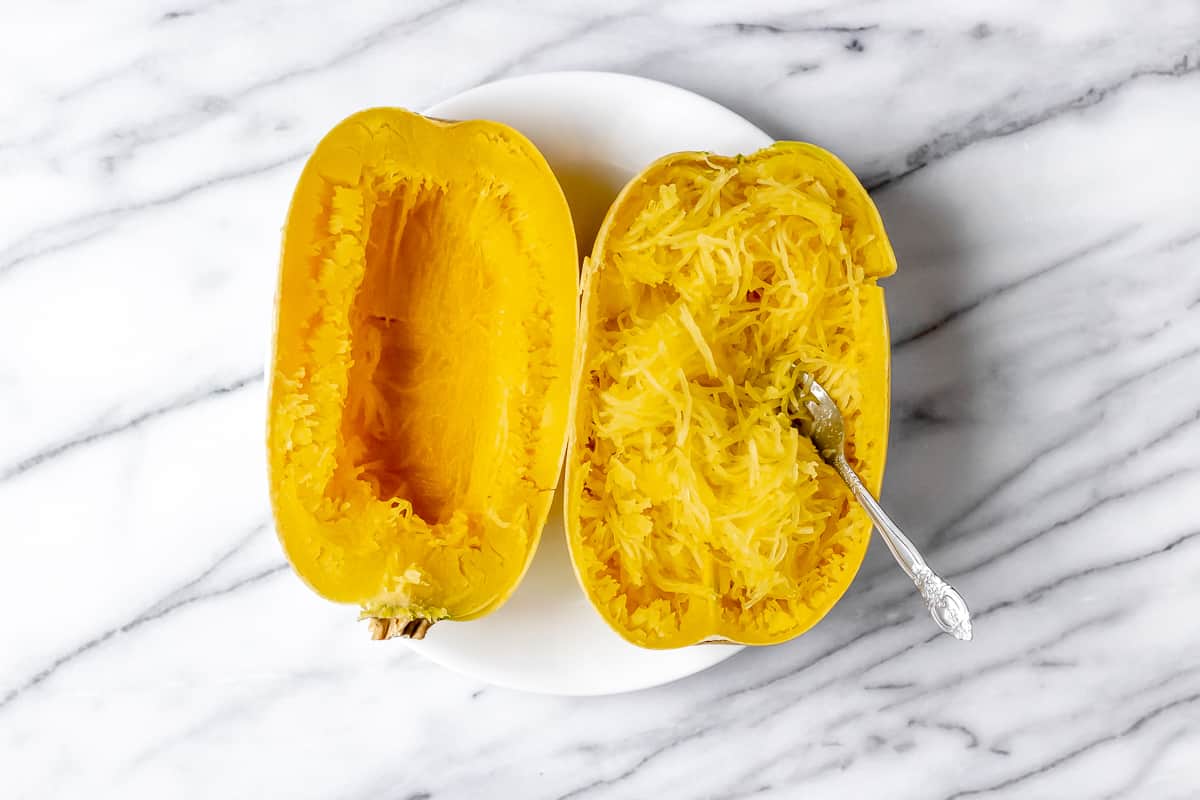 Spaghetti squash cut in half with the strands removed with a fork in one half.