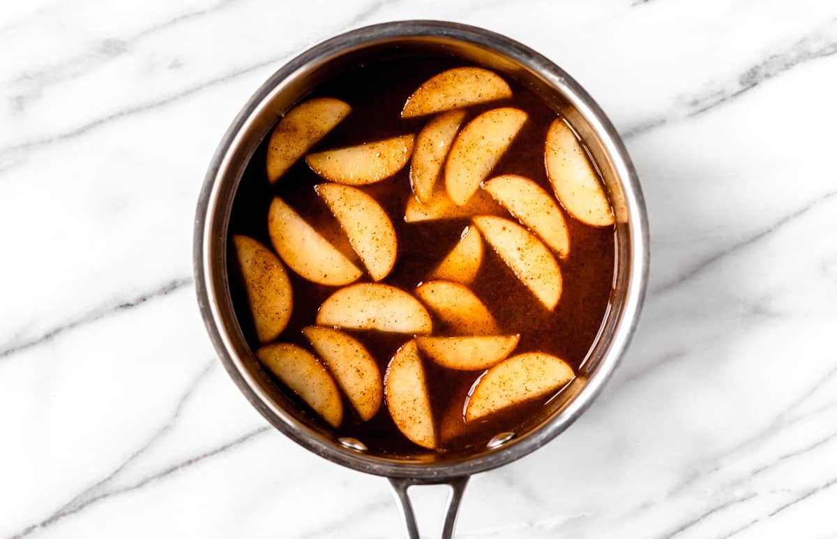 Cinnamon apples and cider cooking in a saucepan.