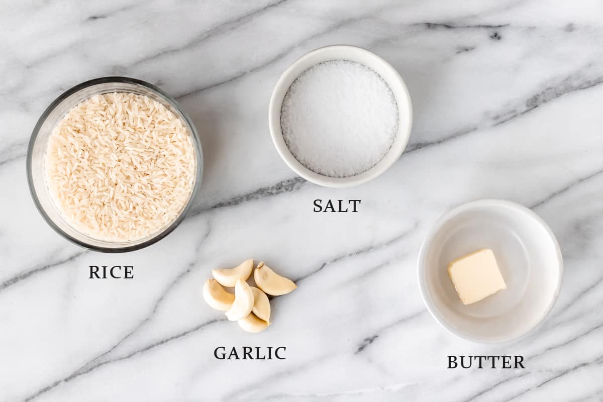 Ingredients to make garlic rice on a marble table with text overlay.