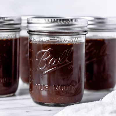 3 canning jars of homemade beef stock with a white background.