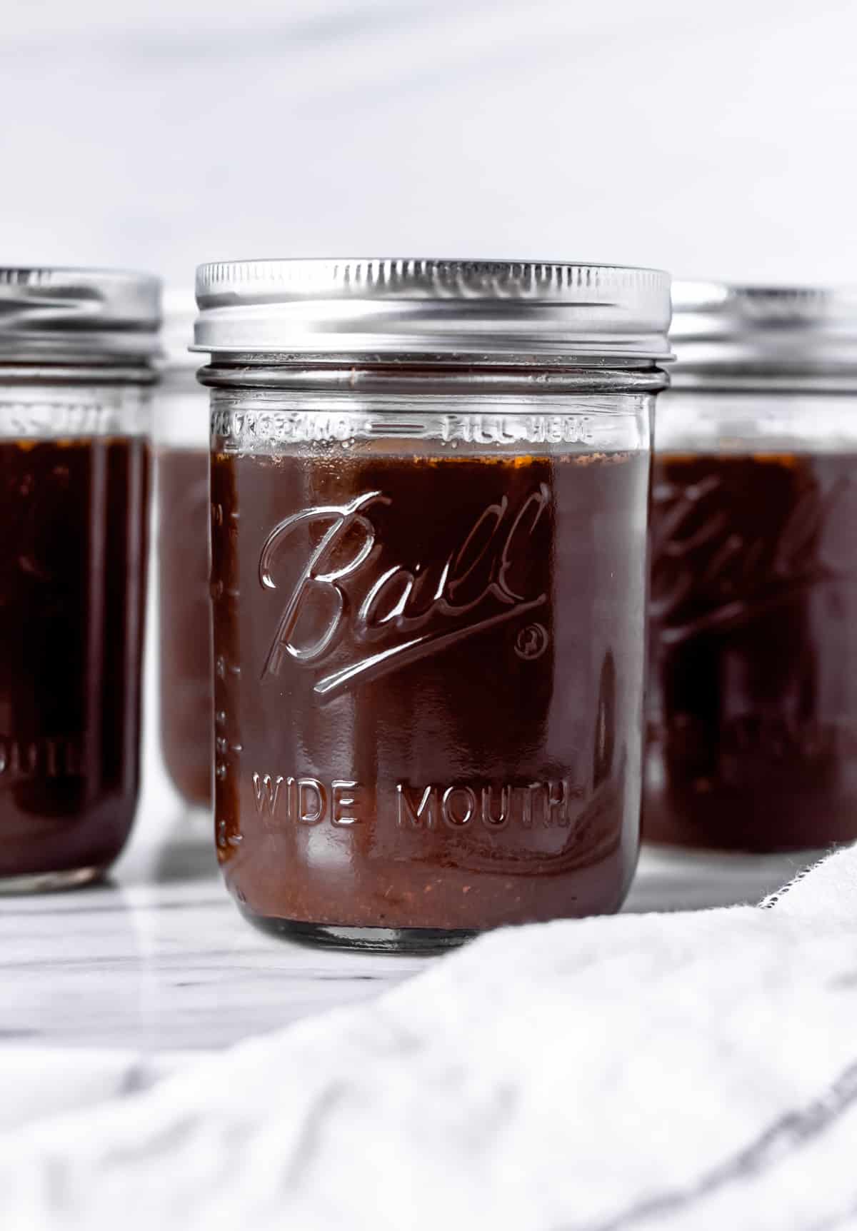 3 canning jars of homemade beef stock with a white background.