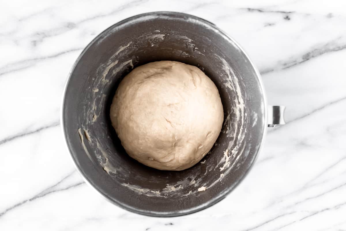A smooth ball of dough in a silver mixing bowl.