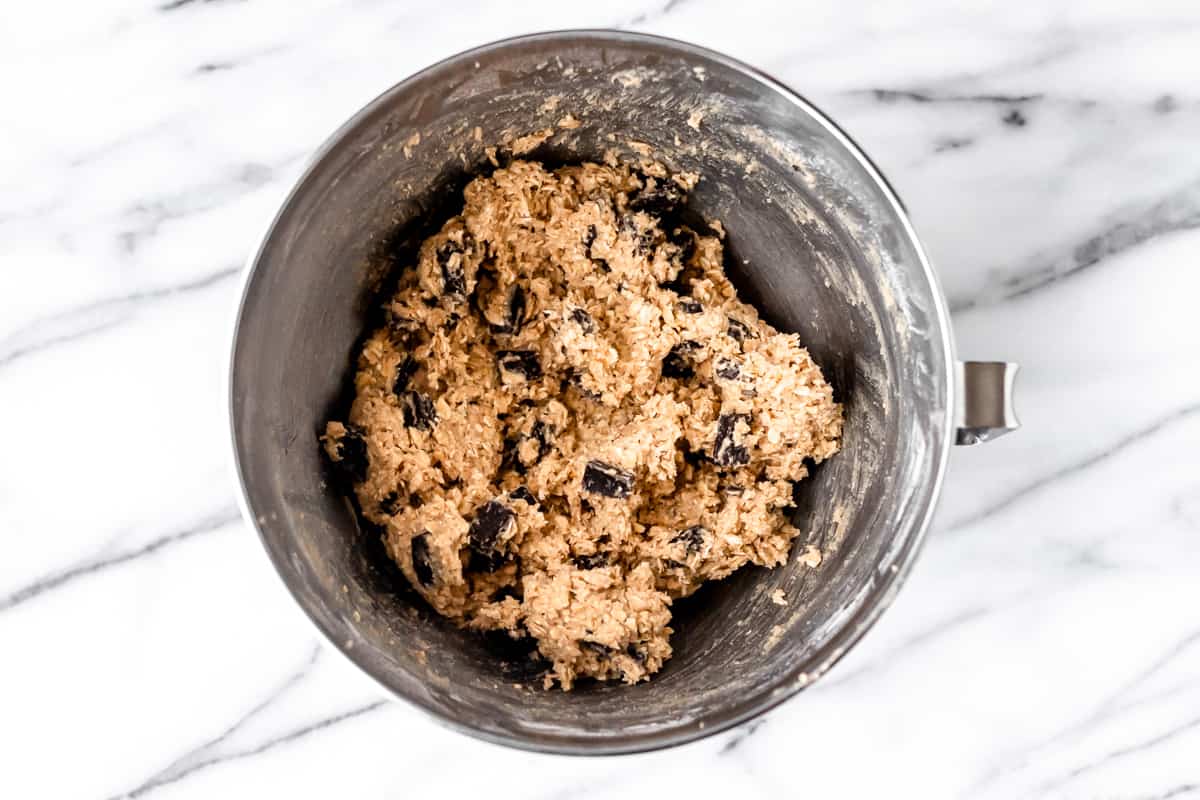 Oatmeal chocolate chunk cookie dough in a silver mixing bowl.