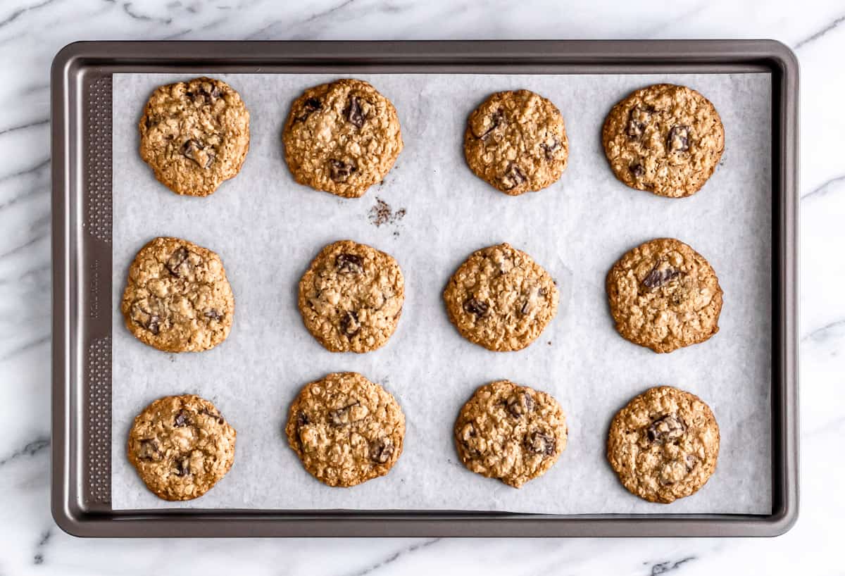 Baked oatmeal chocolate chip cookies on a parchment paper lined baking sheet.