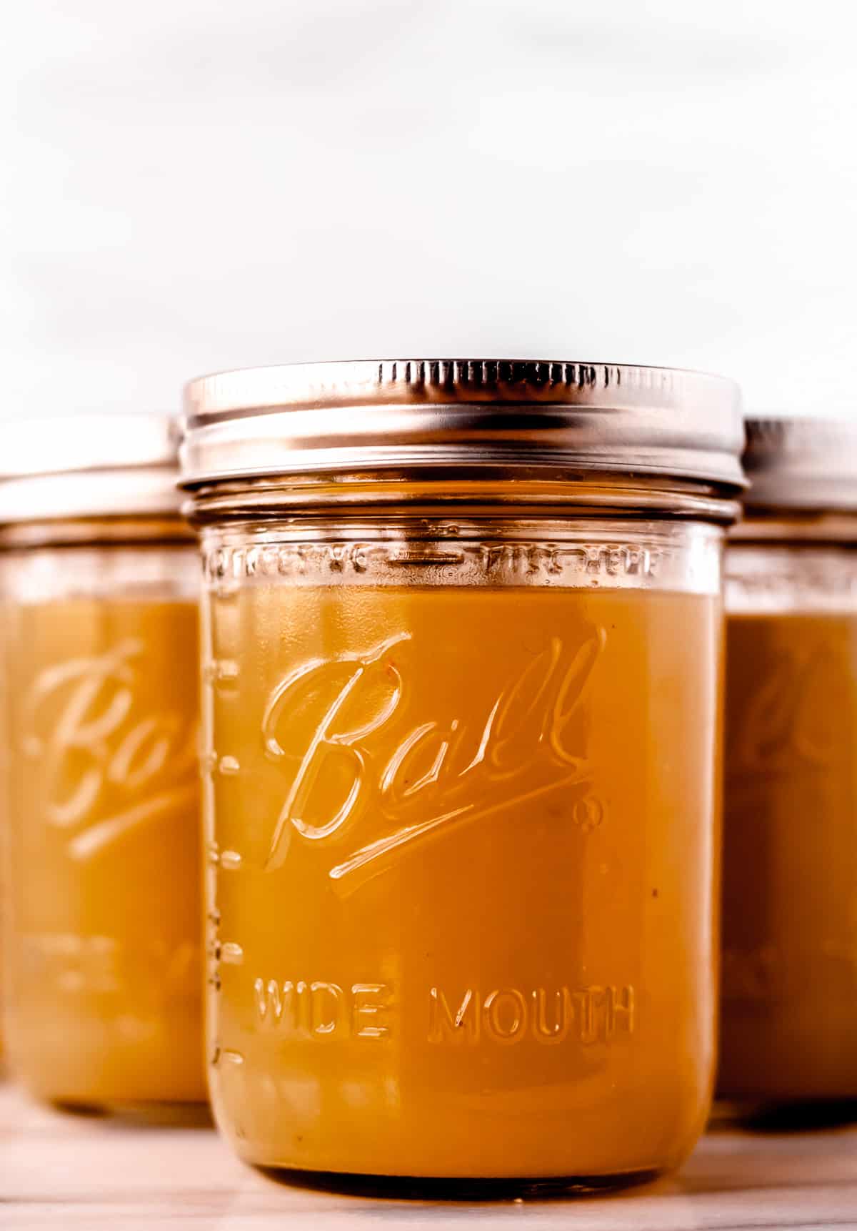 Three canning jars filled with homemade chicken stock.