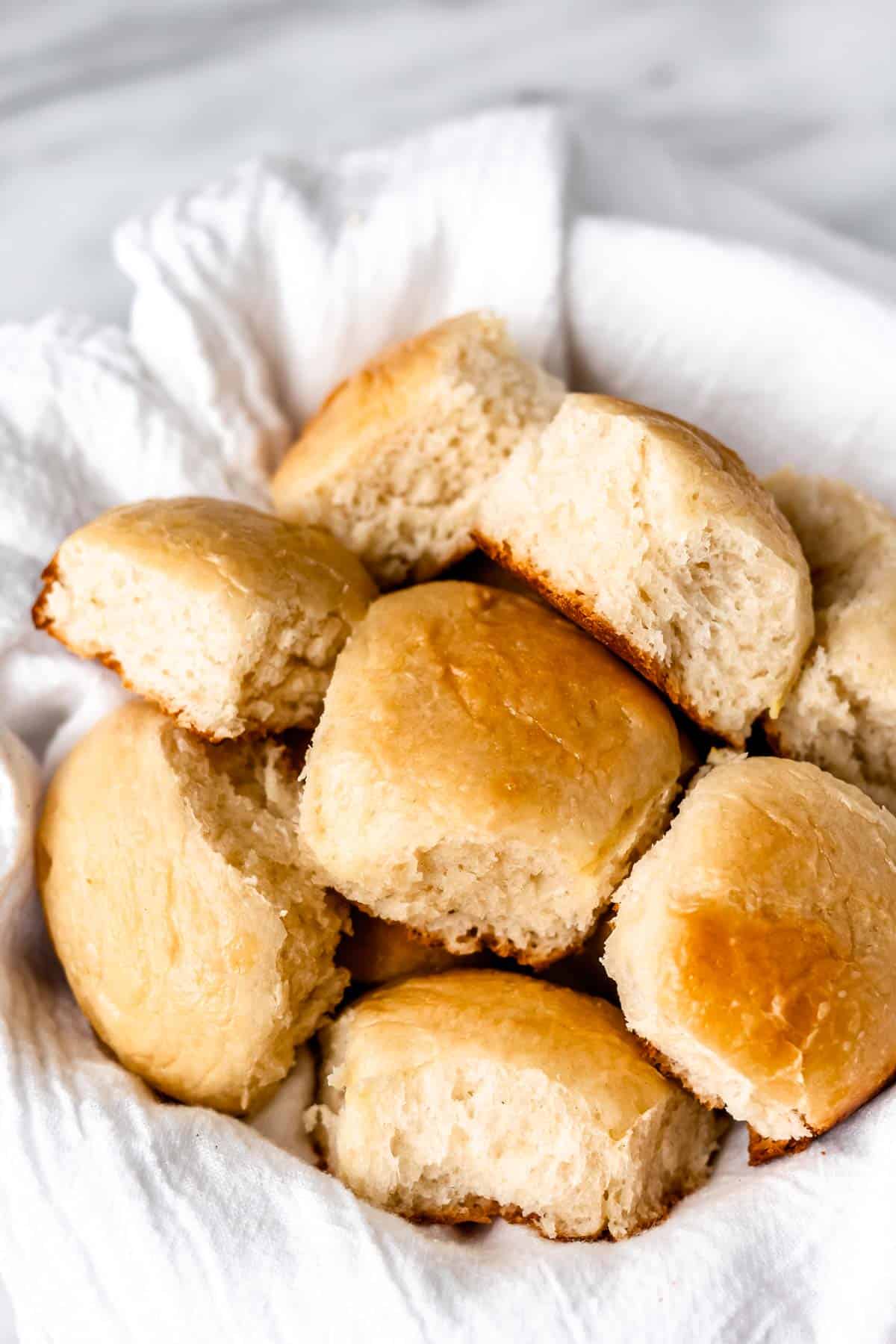 Dinner rolls in a white towel lined bowl.