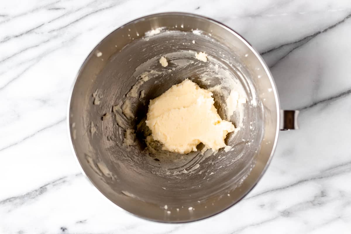 Butter and sugar creamed together in a silver mixing bowl over a marble background.