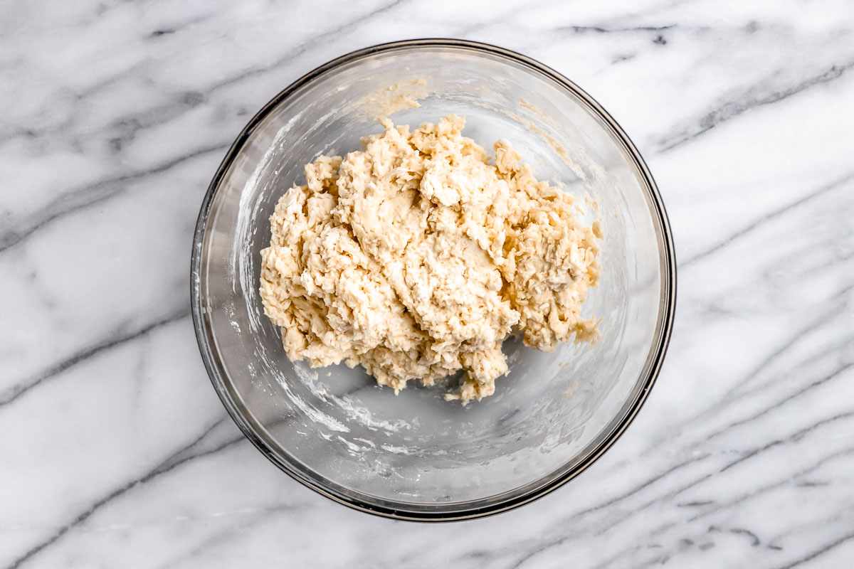 Plain scones dough in a glass bowl on a marble background.