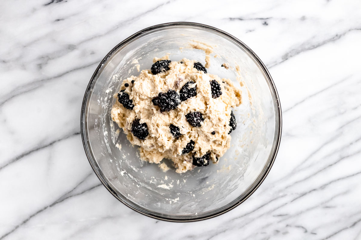 Blackberry scones dough in a glass bowl on a marble background.