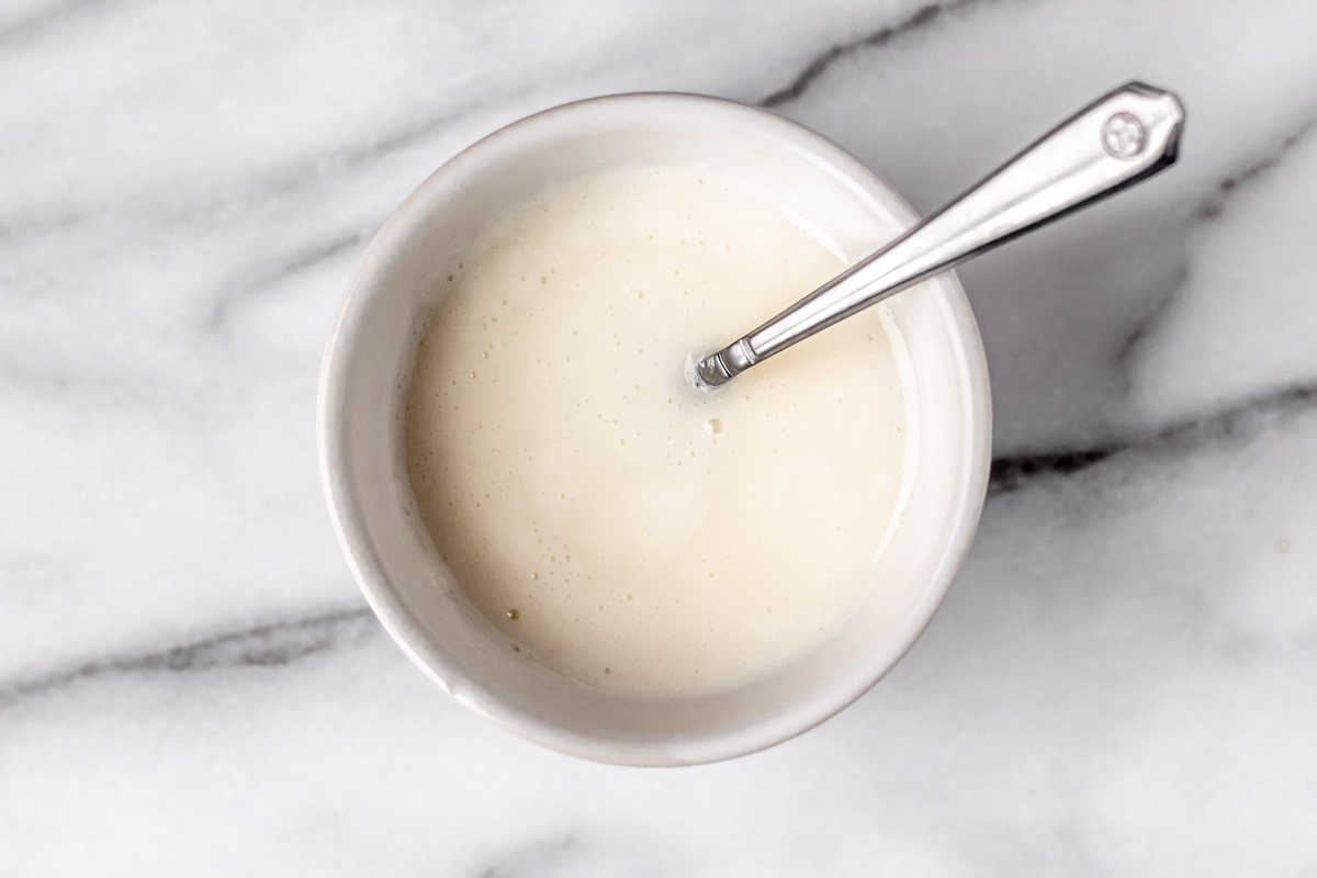 Vanilla glaze for scones in a small white bowl with a spoon in it.