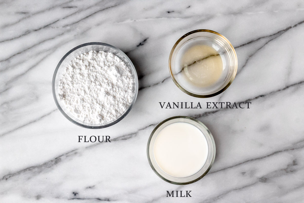 Ingredients needed to make vanilla glaze on a marble background with text overlay.