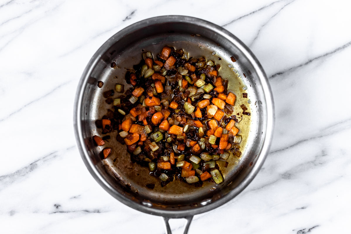 Overhead view of caramelized mirepoix in a silver sauce pan.