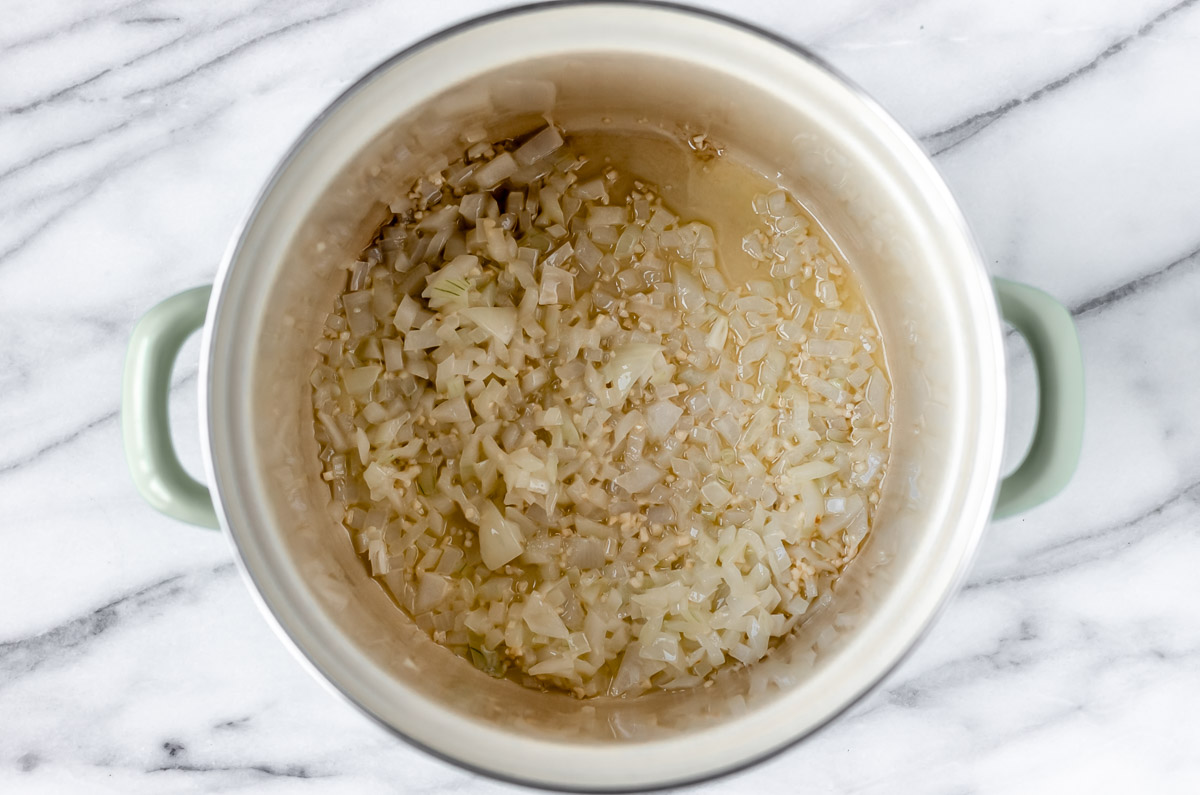 Onions and garlic cooking in the bottom of a stock pot.