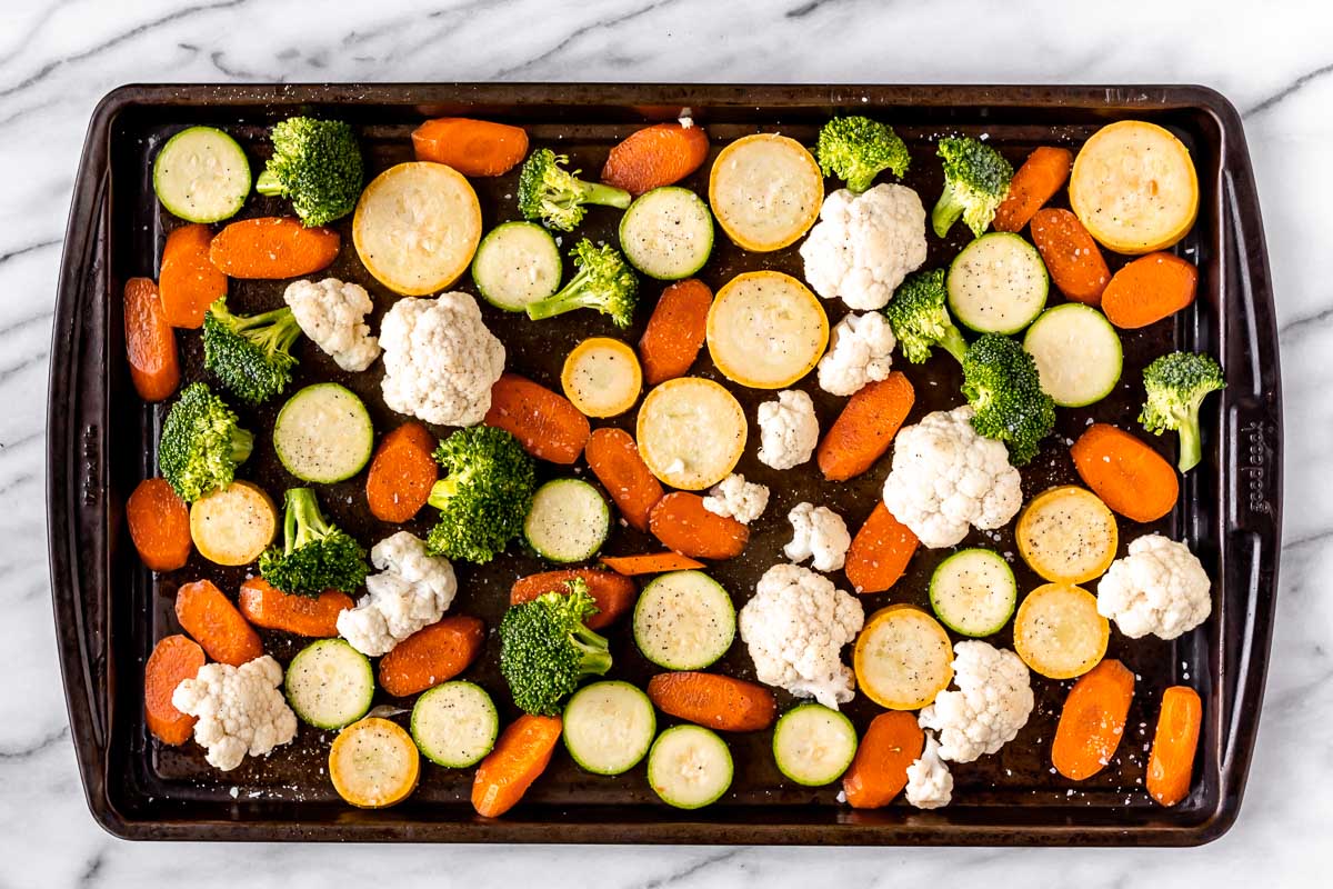 Raw vegetables spread out onto a sheet pan.