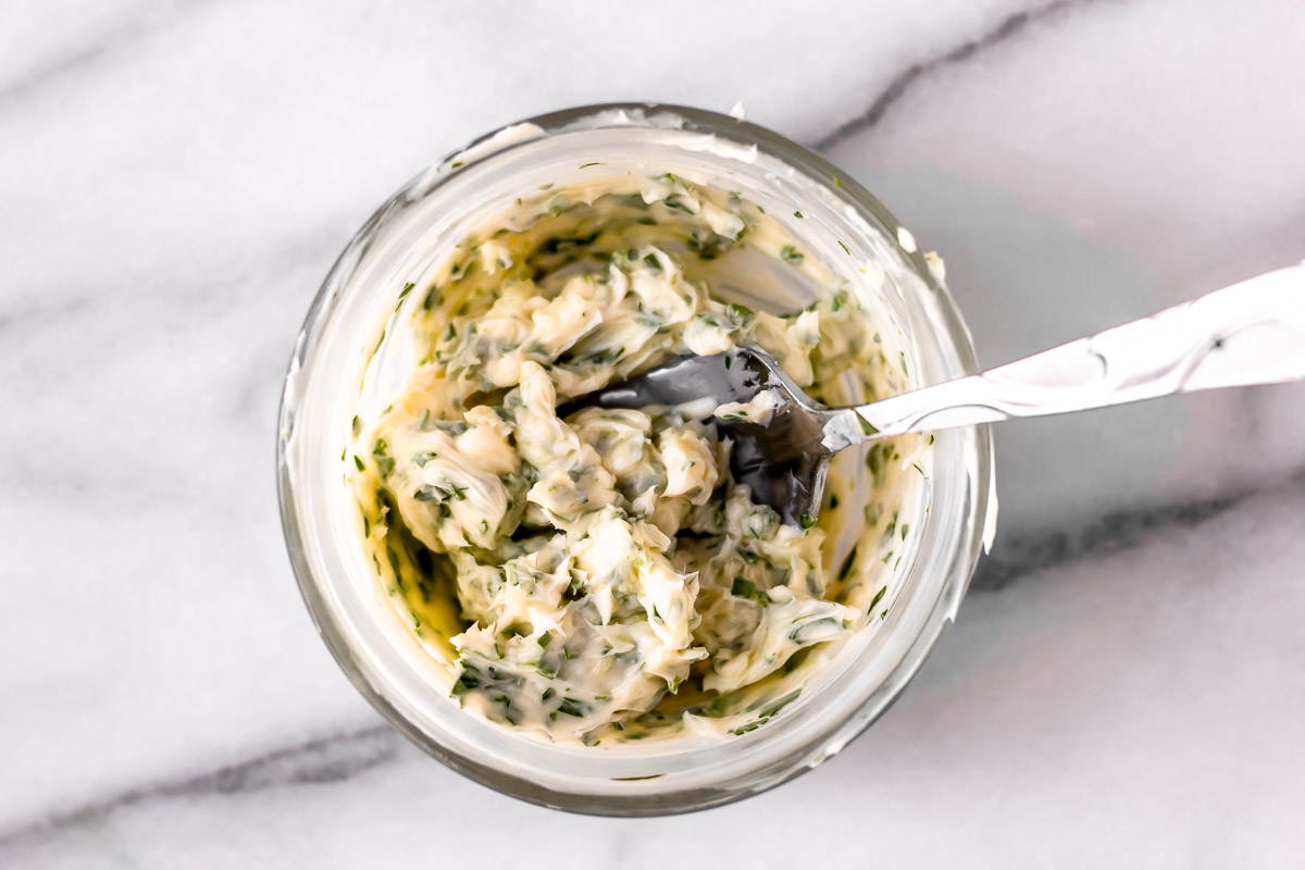 Garlic herb butter in a small bowl with a fork.