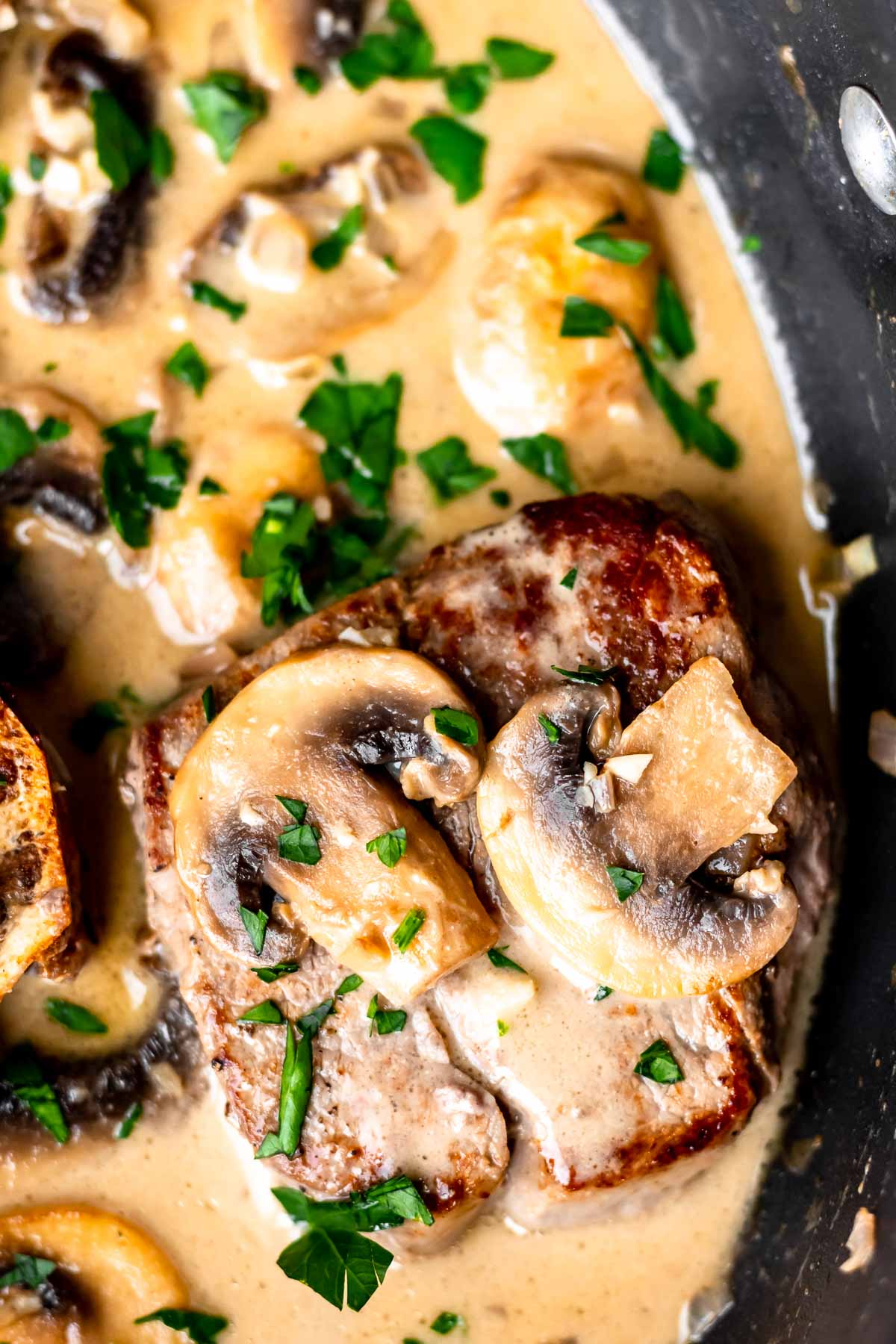 Overhead of a filet mignon with mushroom sauce on it in a skillet.