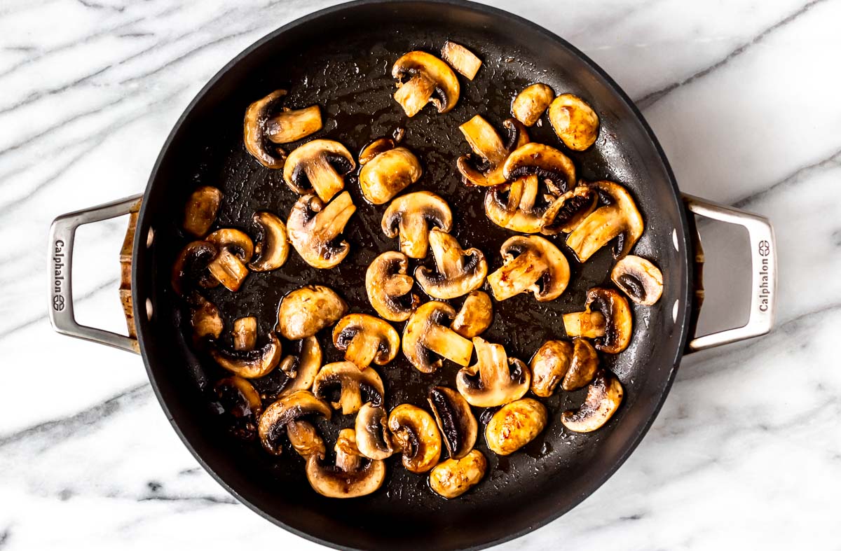 Mushrooms cooking in a skillet.