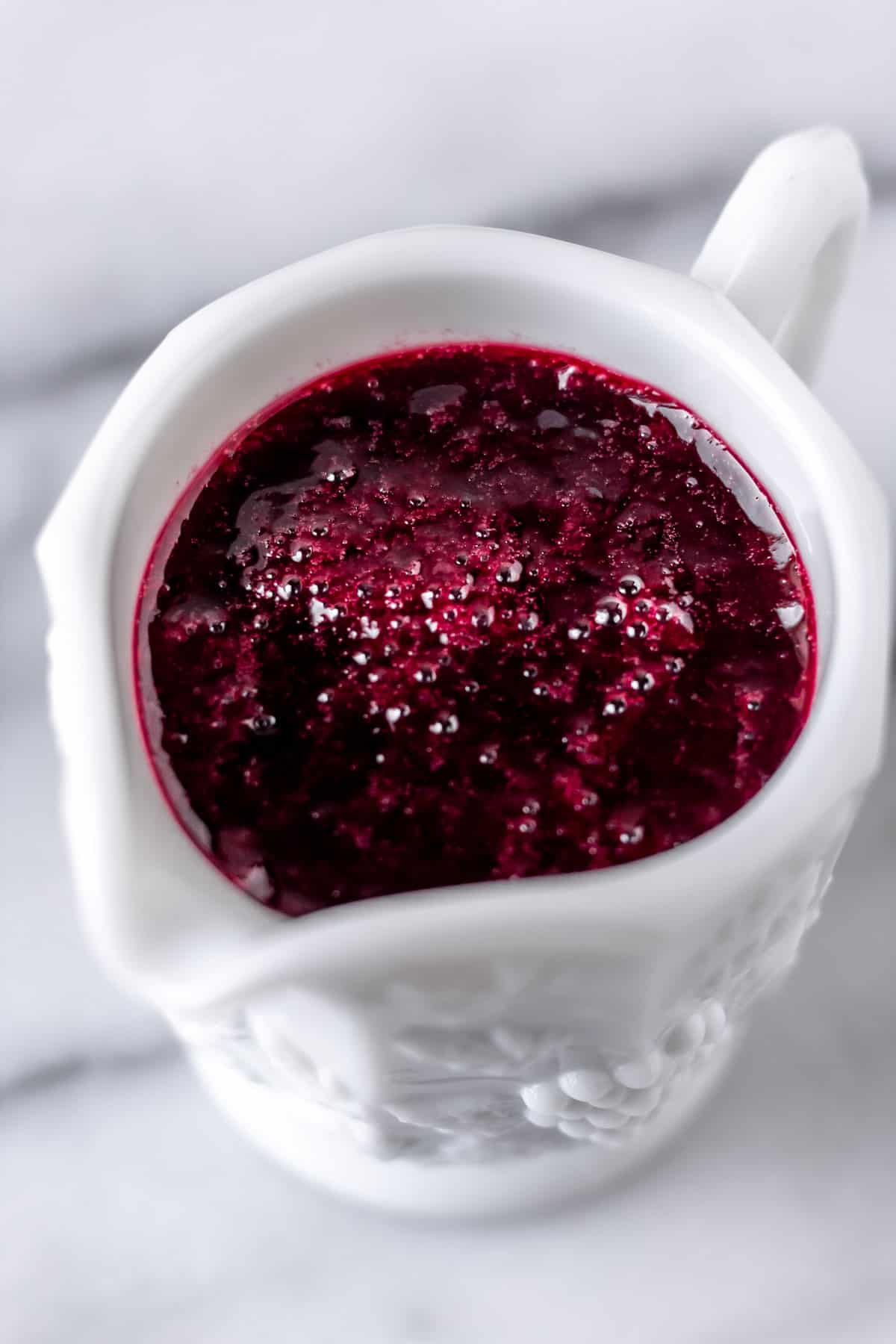 Blackberry syrup in a cup on a marble background.