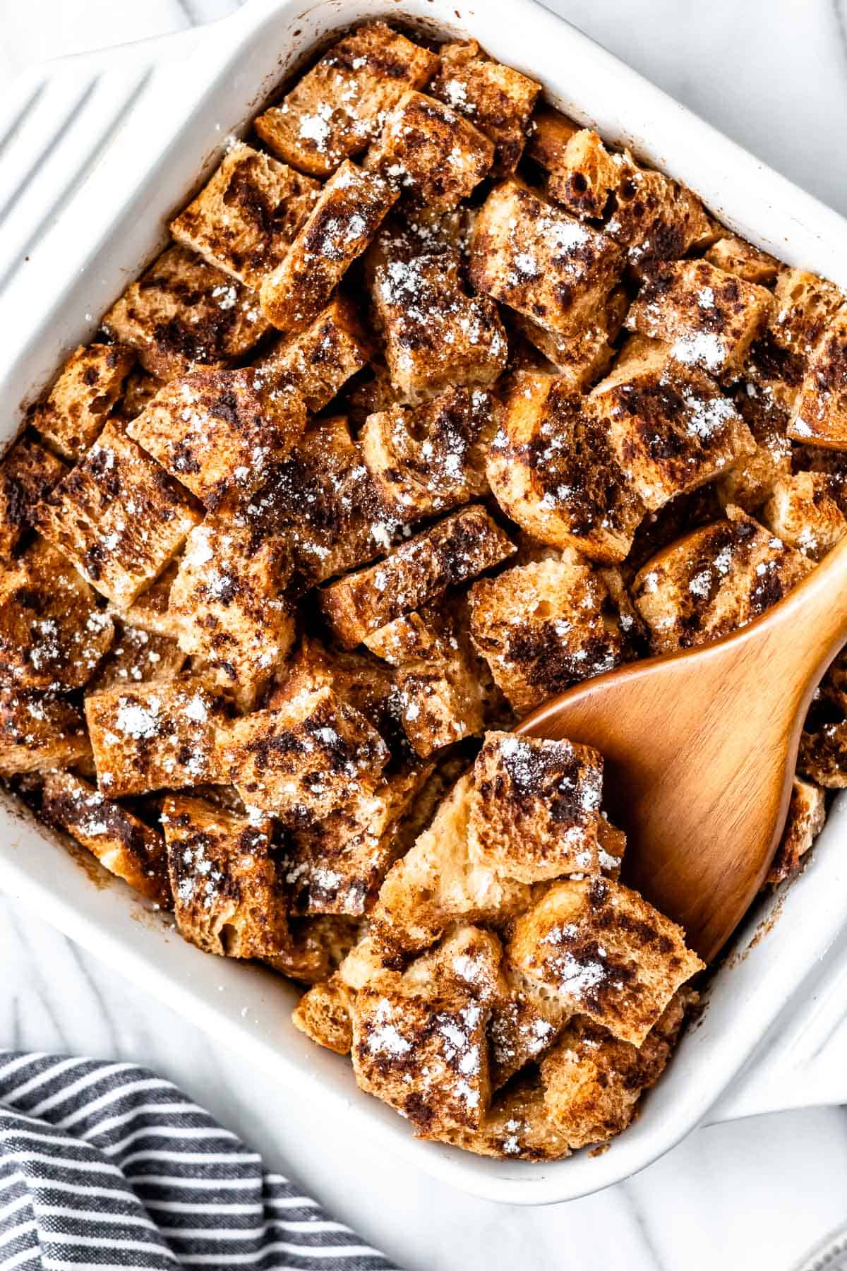 Overhead of a French Toast Casserole with a wood server lifting some up.