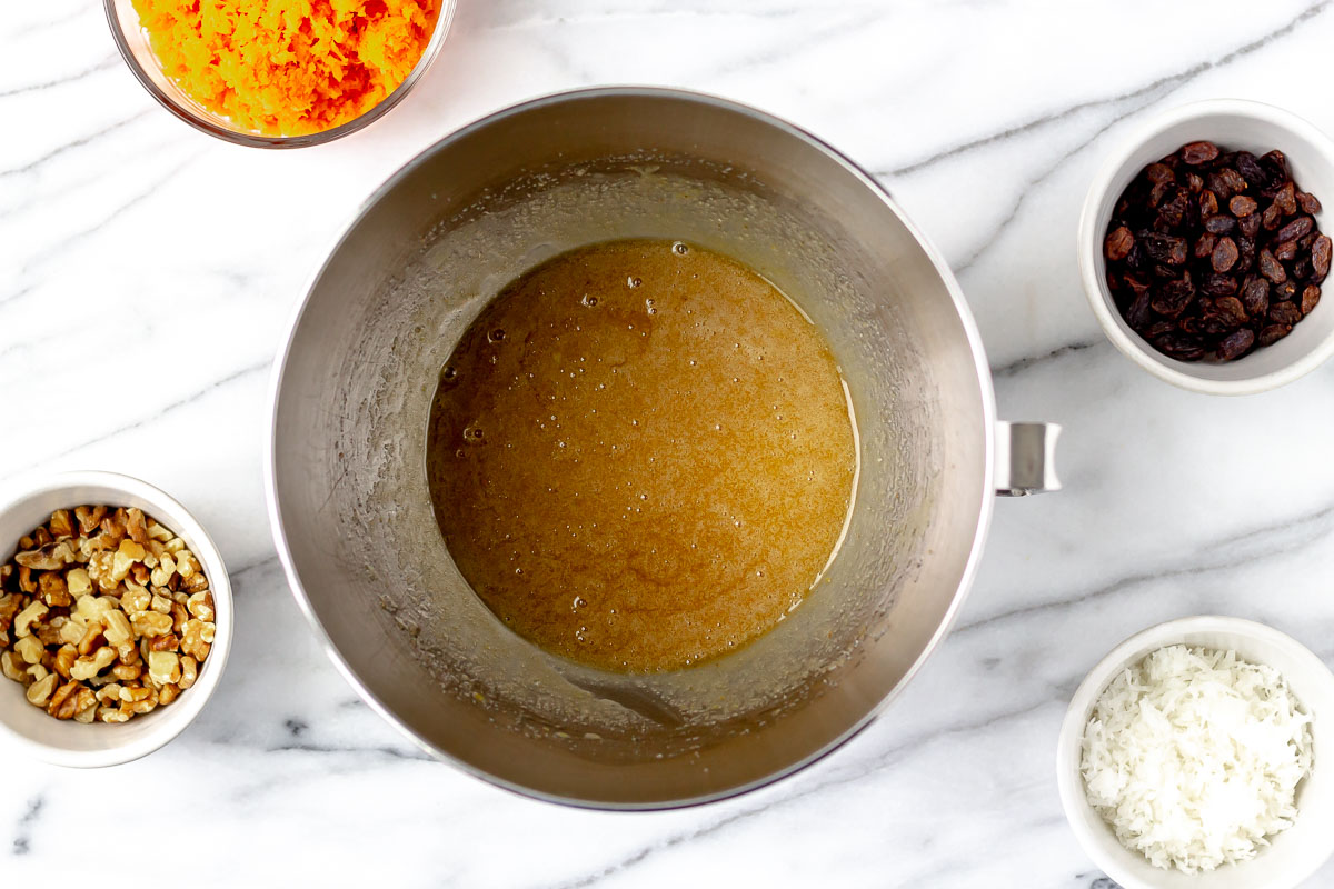 Sugar. brown sugar. eggs and oil combined in a silver mixing bowl.