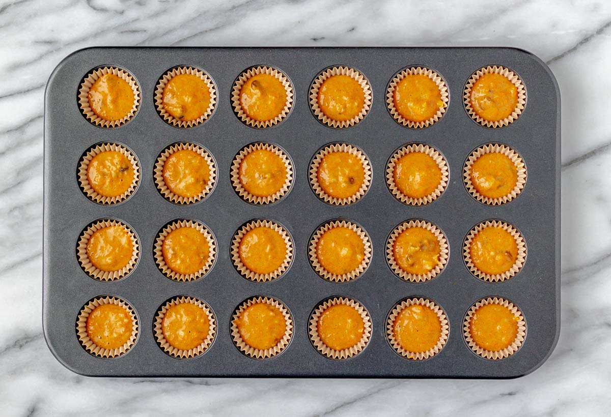 Mini cupcake pan filled with carrot cake batter.