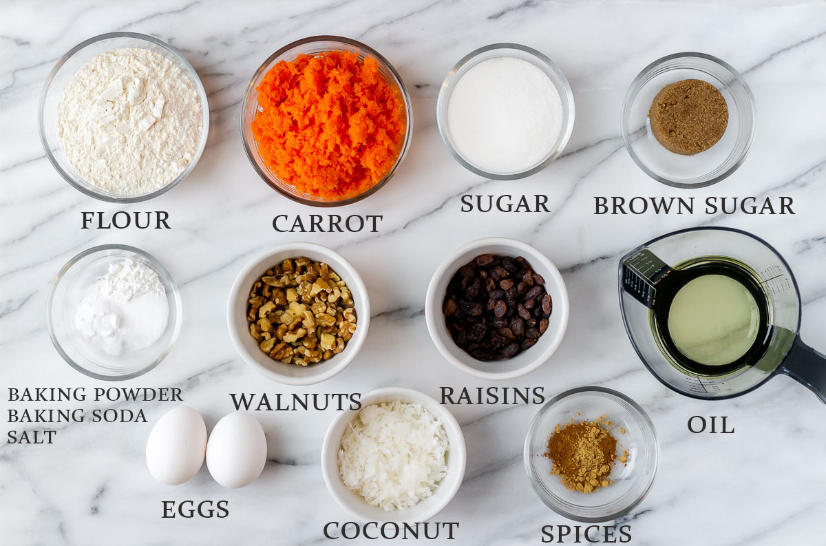 Ingredients to make carrot cake cupcakes on a marble background with text overlay.