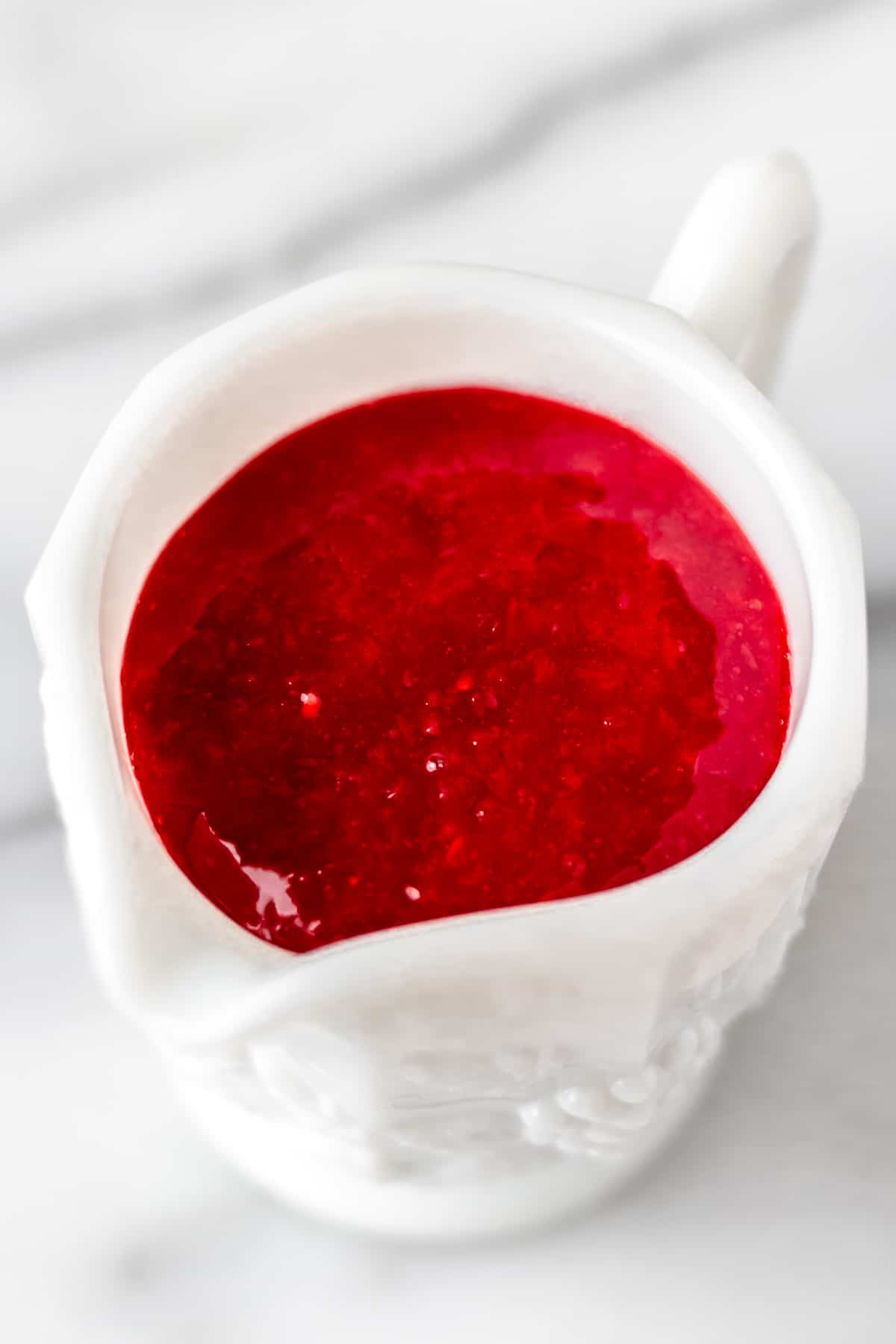 Raspberry sauce in a white cup.