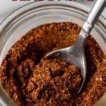 A jar of taco seasoning with a spoon in it and text overlay.