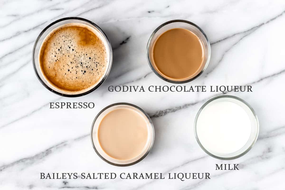 Ingredients needed to make a Baileys Salted Caramel Mocha Latte on a marble background with text overlay.