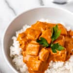 Butter paneer on a plate of rice and in with text overlay.