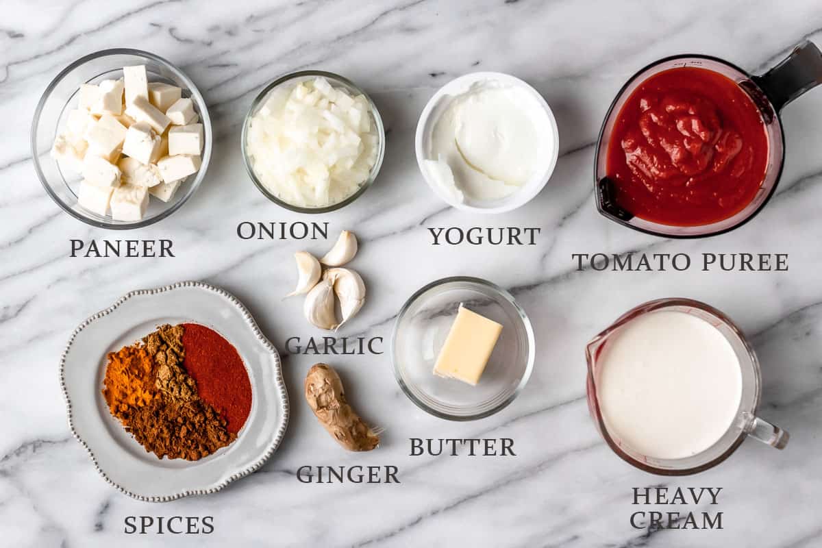 Ingredients to make butter paneer on a marble background with text overlay.