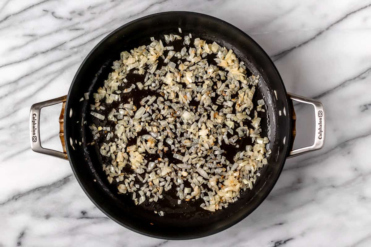 Finely diced onions cooking in butter in a skillet.