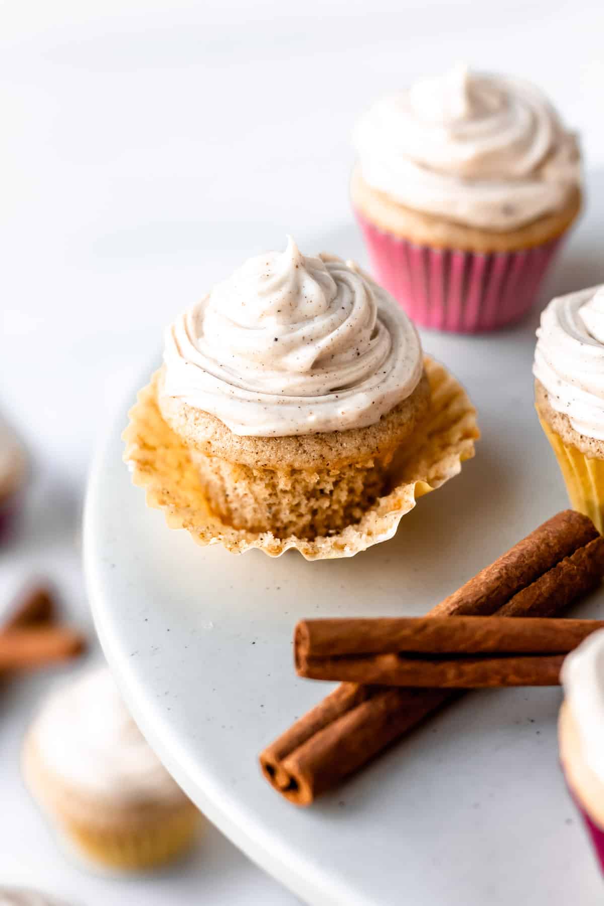 Mini chai cupcakes on a cake stand with cinnamon sticks.