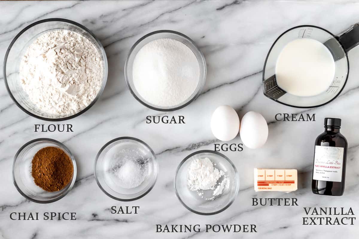 Ingredients needed to make chai cake on a marble background with text overlay.