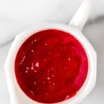 Raspberry sauce in a white pitcher with text overlay.