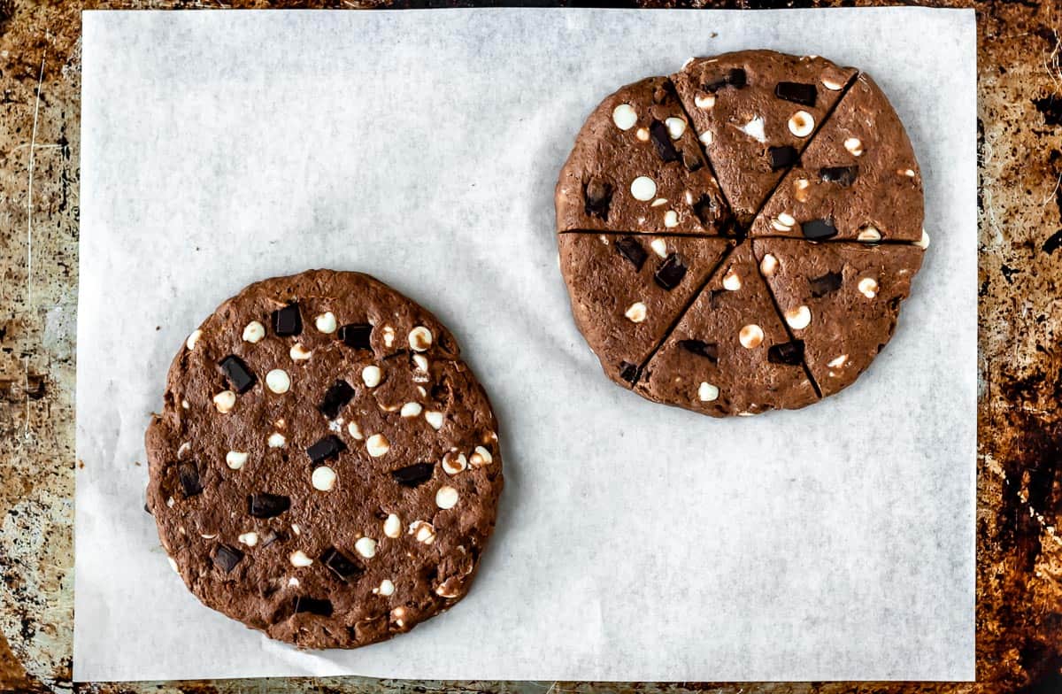 Triple chocolate scones dough shaped into two disks with one of them cut into 6 triangles.