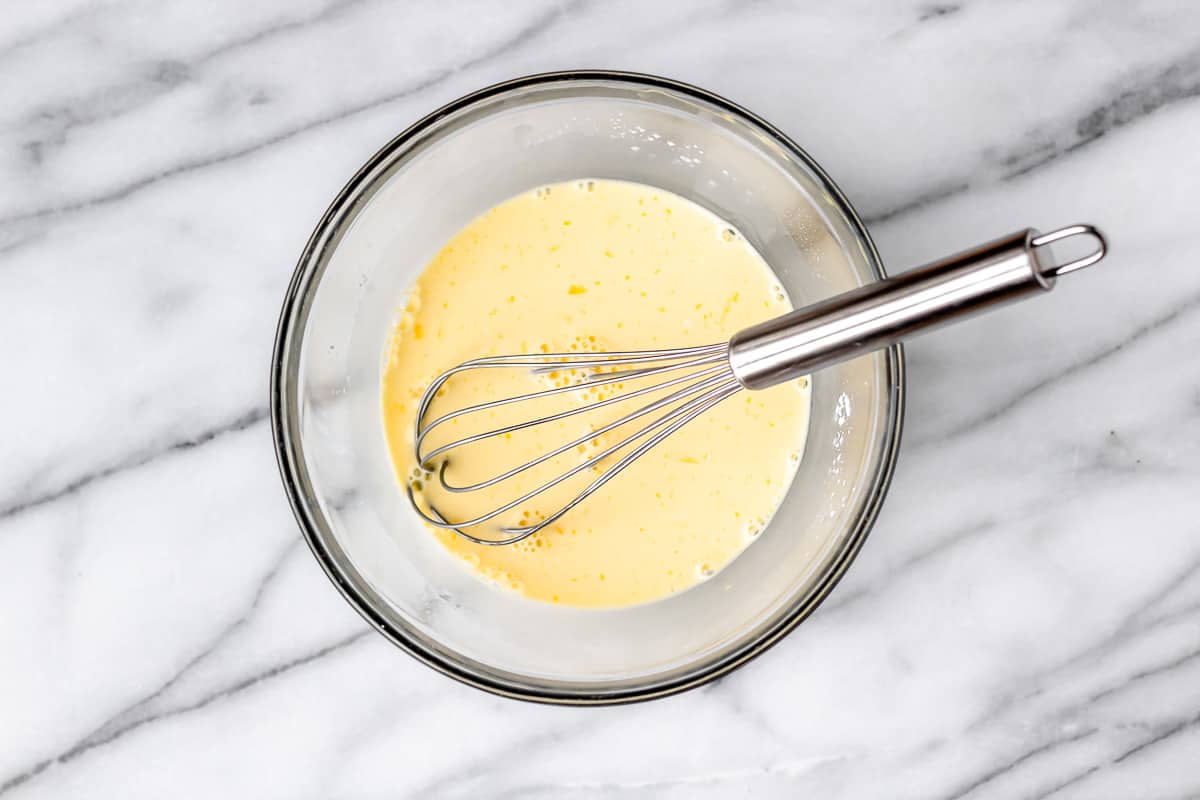 Eggs, cornstarch and milk whisked together in a glass bowl.
