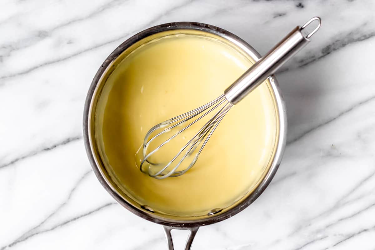 Pastry cream in a sauce pot with a whisk.