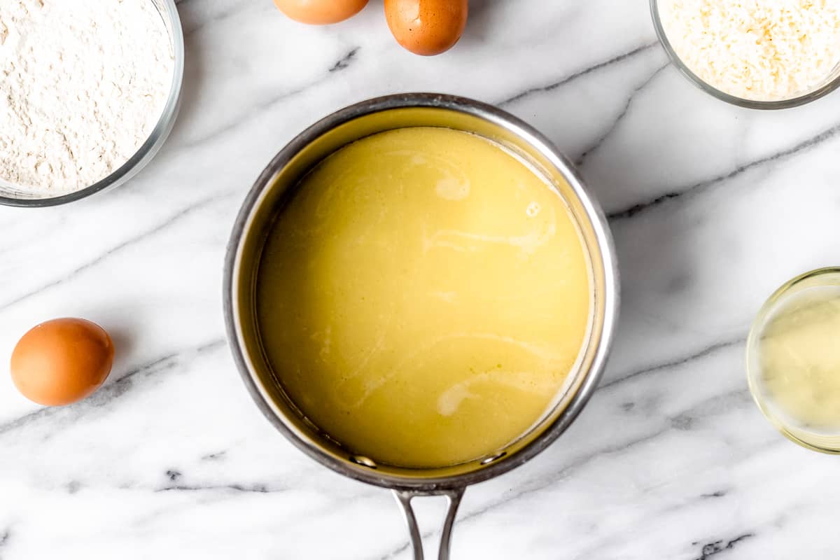 Melted butter in a pot over a marble table with other ingredients around it.
