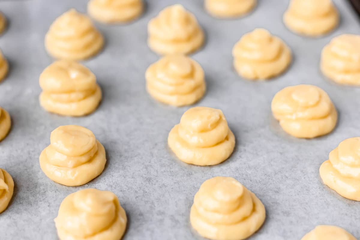 Gougeres piped out onto a parchment lined baking sheet.