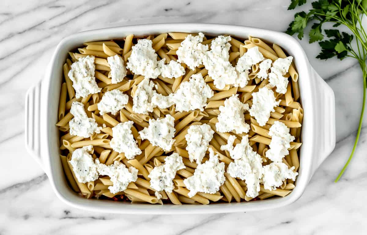 Two layers of pasta, cheese and sauce in a casserole dish.