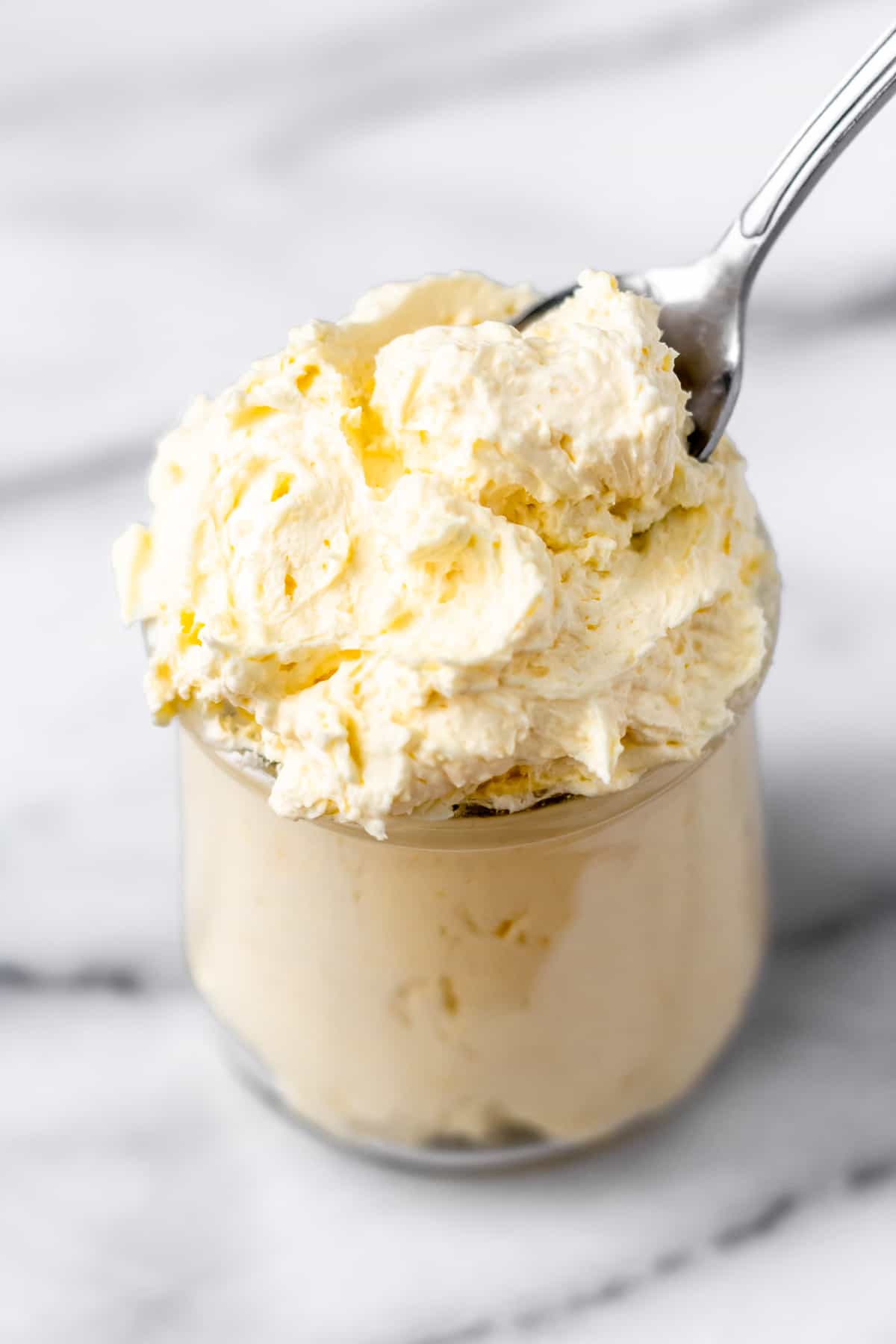 A jar full of pastry cream alternative with a spoon stuck into it.