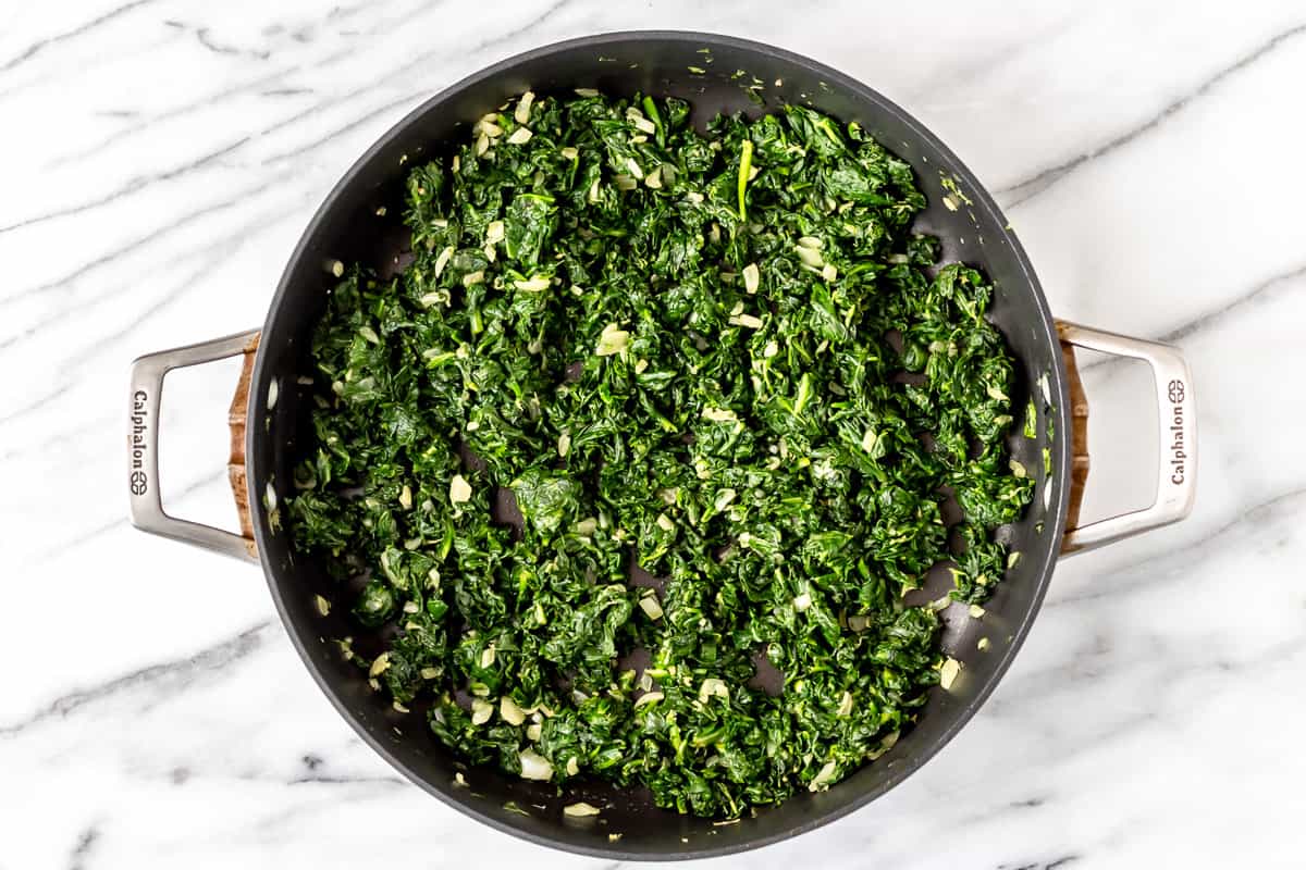 Spinach and onion cooking in a skillet.