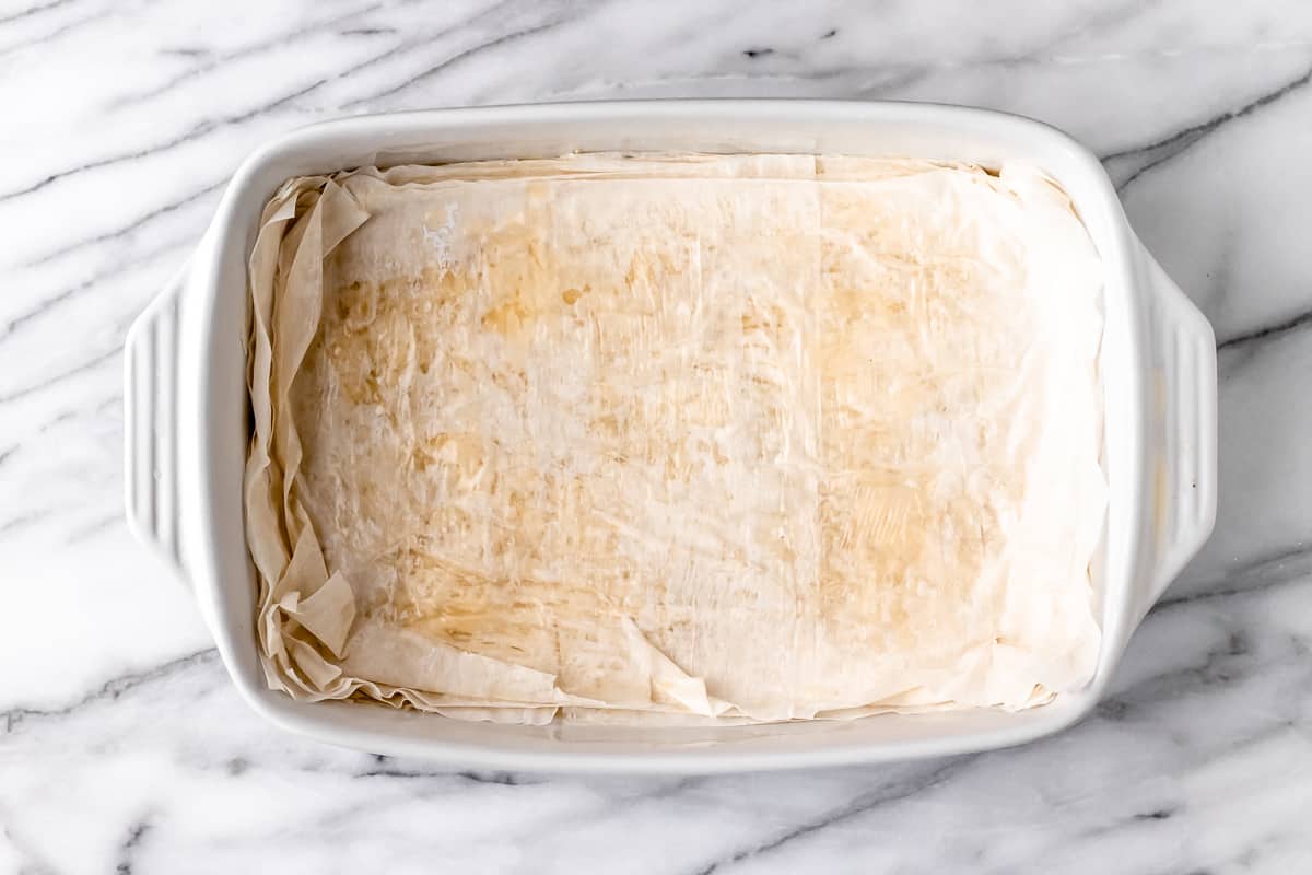 Layers of phyllo dough in a rectangular casserole dish.