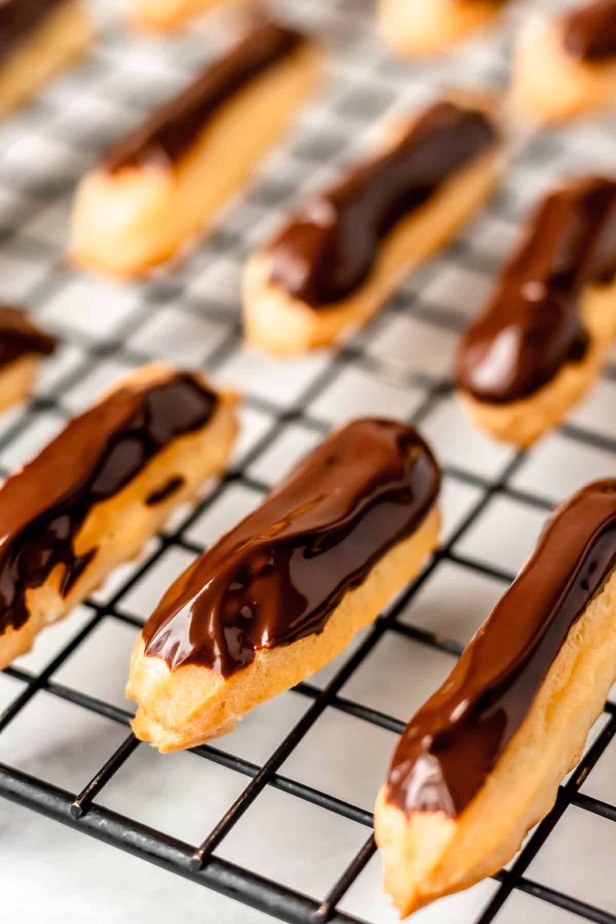Close up of chocolate mini eclairs in a cooling rack.