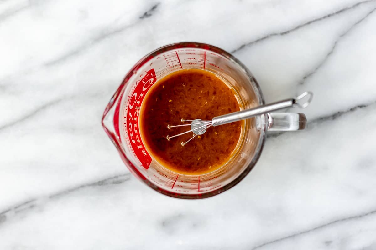 Orange glaze ingredients mixed together in a measuring cup.